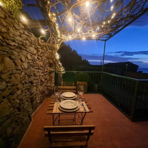 Una mesa con platos y copas de vino en un patio. en Sunset Manarola, en Manarola
