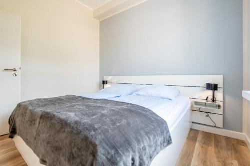 a bedroom with a white bed with a gray blanket at Steger-Hüs Wohnung 13 in Rantum