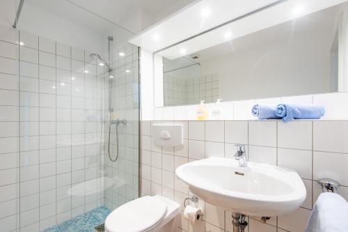 a bathroom with a sink and a toilet and a mirror at Steger-Hüs Wohnung 09 in Rantum