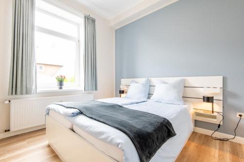 a white bedroom with a large white bed with a window at Steger-Hüs Wohnung 12 in Rantum
