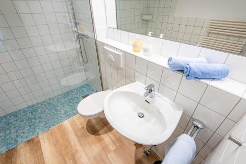 uma casa de banho branca com um lavatório e um chuveiro em Steger-Hüs Wohnung 12 em Rantum