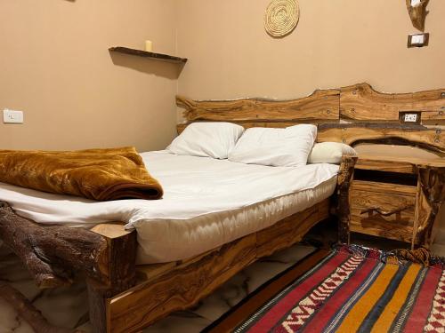 a bedroom with a wooden bed with white sheets and pillows at People to People Siwa in Siwa