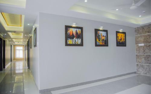 a hallway with three framed paintings on a wall at Hotel S R Castle in Port Blair