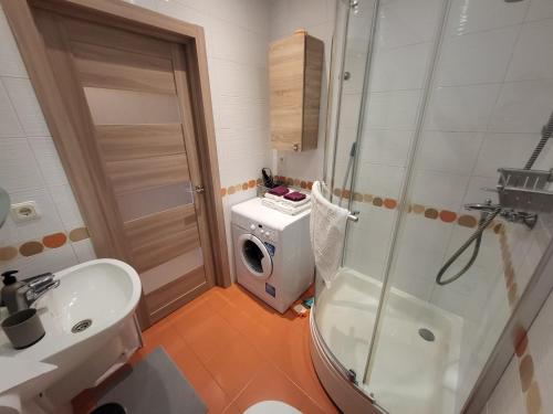 een badkamer met een douche, een wastafel en een wasmachine bij Solaris Studio Apartments in Rīga