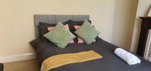 Una cama con almohadas rosas y verdes. en Coventry Spacious Rooms In City, en Coventry