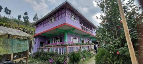 a purple house with a man standing in front of it at Hillsation Thulung Homestay in Kalimpong