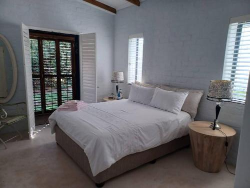 a white bedroom with a large bed and windows at Chillilabombwe in Pringle Bay