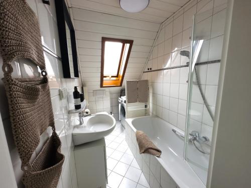 Baño blanco con bañera y lavamanos en DG-Wohnung mit sonnigem Balkon en Marburg an der Lahn