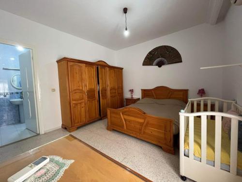a bedroom with a wooden bed and a crib at Ahlem palmeraies résidence in La Marsa