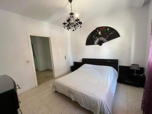 a bedroom with a white bed and a chandelier at Ahlem palmeraies résidence in La Marsa
