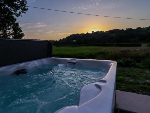 a hot tub with the sunset in the background at Plas Glan Yr Afon in Abergele