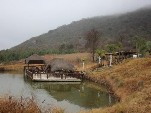 a river with a group of buildings on a hill at Emahlathini Guest Farm in Piet Retief