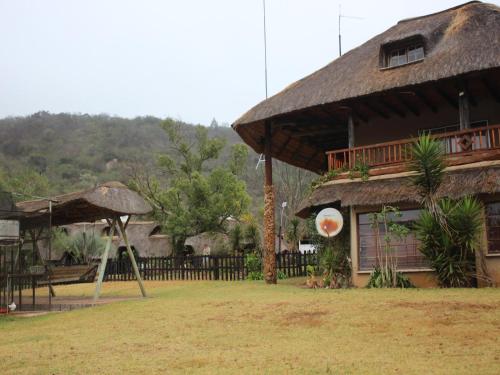 a house with a thatch roof and a playground at Emahlathini Guest Farm in Piet Retief