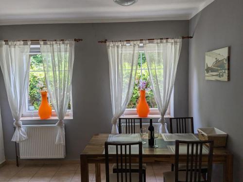 a dining room with two orange vases on the windows at Rekreační dům KRKONOŠE - Ubytování - Holidayhome Lampertice in Lampertice