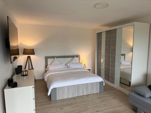 a bedroom with a large bed and a mirror at Modernes Apartment mit 180° Bergblick in Buchenberg