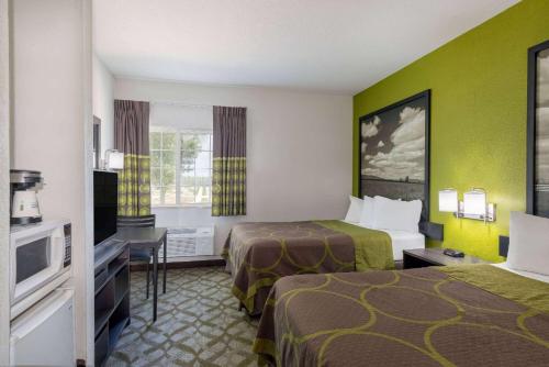 a hotel room with two beds and a television at Super 8 by Wyndham De Soto in De Soto