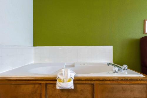a bathroom with a tub and a green wall at Super 8 by Wyndham De Soto in De Soto