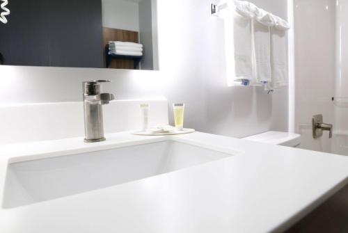 Baño blanco con lavabo y espejo en Microtel Inn & Suites by Wyndham Charlotte/Northlake en Charlotte