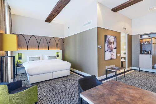 a bedroom with a bed and a table and chairs at Hotel Nassau Breda, Autograph Collection in Breda