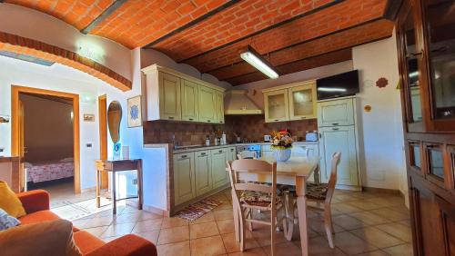 una cocina con armarios verdes y una mesa con sillas en Spicchio di Luna - Casa Vacanze, en Albiano
