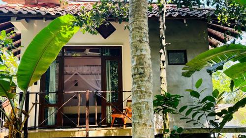 a house with a balcony with a palm tree at Dosemo Cabana in Induruwa