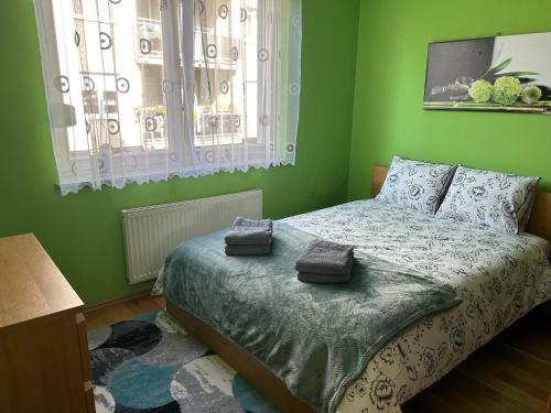 a green bedroom with a bed with two towels on it at Quiet enclave near the airport in Wrocław