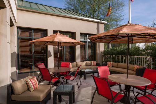 un patio avec des tables, des chaises et des parasols dans l'établissement Hilton Garden Inn Phoenix Airport North, à Phoenix