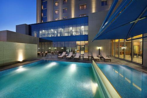 a swimming pool with chairs and a building at Hilton Garden Inn Tabuk in Tabuk