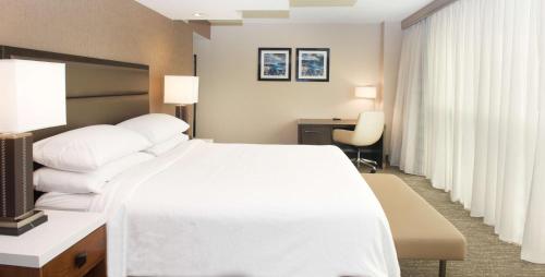 a hotel room with a large white bed and a desk at Embassy Suites by Hilton Seattle North Lynnwood in Lynnwood