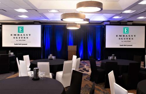 a conference room with black tables and chairs and blue curtains at Embassy Suites by Hilton Seattle North Lynnwood in Lynnwood