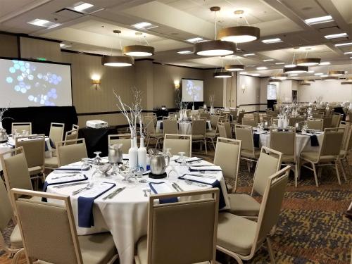 a conference room with tables and chairs and a screen at Embassy Suites by Hilton Seattle North Lynnwood in Lynnwood