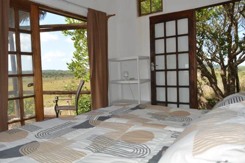 a bedroom with a bed with a view of a field at Winterdodgers Backpackers and Campsite in Sodwana Bay