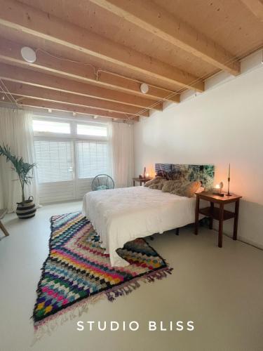 a bedroom with a large bed and a rug at Studio Bliss in Oud-Gastel