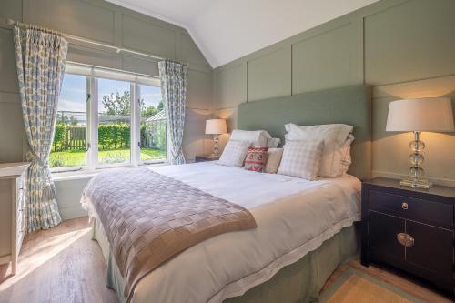 ein Schlafzimmer mit großem Bett und Fenster in der Unterkunft Elegant luxurious cottage - The Dove House in Ipswich