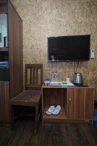 a room with a tv and a bench and a chair at Hotel Soreang in Bandung