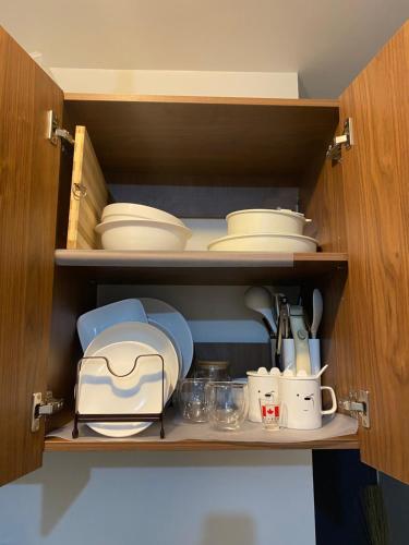 a cupboard with plates and bowls and utensils at Seaside Serenity w/ Sunrise @ Saekyung Village One in Lapu Lapu City