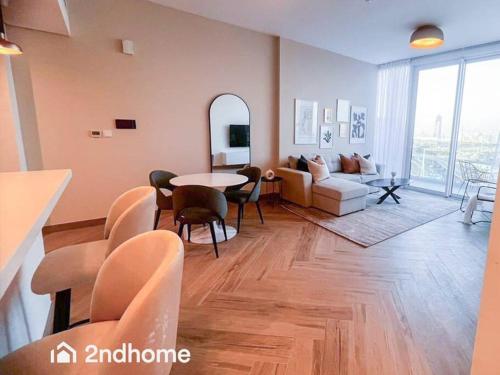 a living room with a couch and a table and chairs at Homey 1 Bedroom with Relaxing Zabeel Park View in Dubai