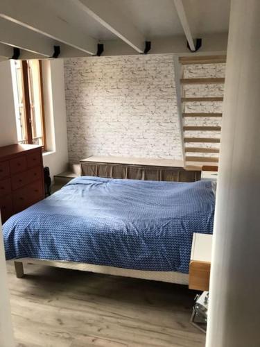 Un dormitorio con una cama azul y una pared de ladrillo en Élégant F2 de 70m2 à 1km du centre ville., en Metz