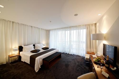 a hotel room with a bed and a television at Lighthouse Golf & Spa Hotel in Balchik
