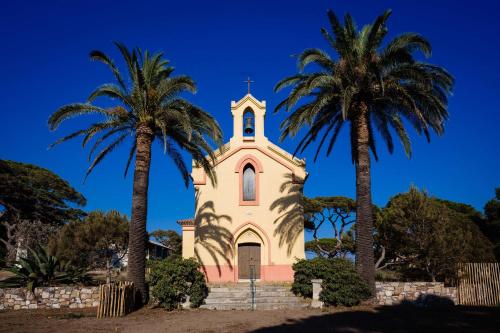 a church with two palm trees in front of it at Le Hameau Des Pesquiers Ecolodge & Spa, Curio Collection By Hilton in Hyères