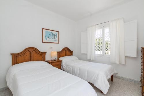 Villa los brezos في بلايا ذي بالما: سريرين في غرفة نوم بجدران بيضاء ونافذة