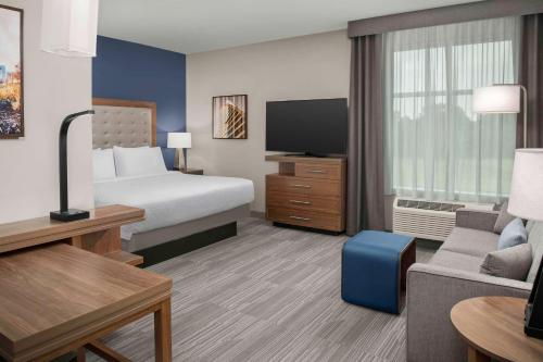 Homewood Suites By Hilton Greenville, NC في غرينفيل: غرفه فندقيه بسرير واريكه