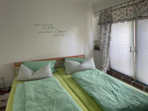 a bedroom with two beds with green sheets and a window at An der Heide. in Braunsteich
