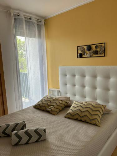 a bedroom with a bed with a white headboard and a window at Beach House Carmen in Monte Gordo