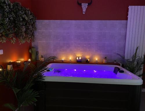 a purple bath tub with candles and lights at House Spa Privatif - Jaccuzi et Sauna in Livry-Gargan