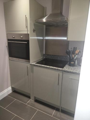 a kitchen with white cabinets and a stove top oven at Harrogate Lifestyle Luxury Serviced ApartHotel in Harrogate