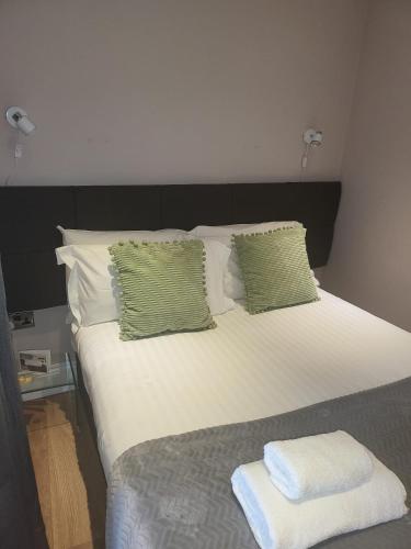a large bed with green and white pillows at Harrogate Lifestyle Luxury Serviced ApartHotel in Harrogate