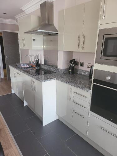 a kitchen with white cabinets and a black counter top at Harrogate Lifestyle Luxury Serviced ApartHotel in Harrogate
