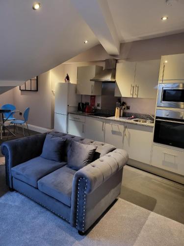 a living room with a blue couch and a kitchen at Harrogate Lifestyle Luxury Serviced ApartHotel in Harrogate