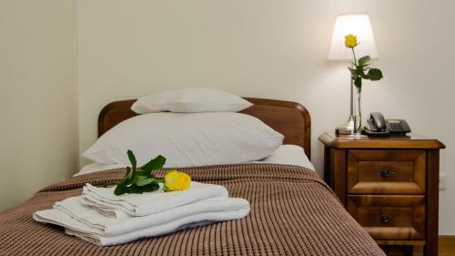 a bedroom with a bed with towels and a phone at Hotel Łazienkowski in Warsaw